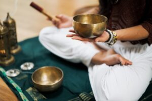 Person in a yoga position holding a singing bowl