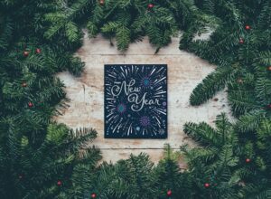 New Year written on chalk board surrounded by pine garlands